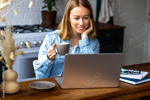Smiling woman with laptop in kitchen at home