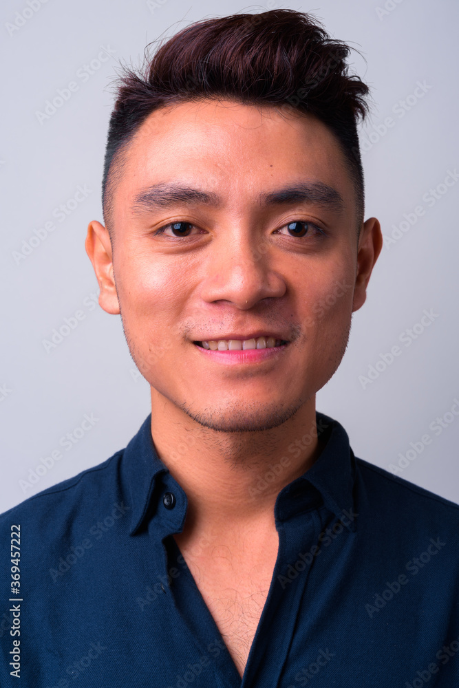 Face of happy young Asian businessman smiling