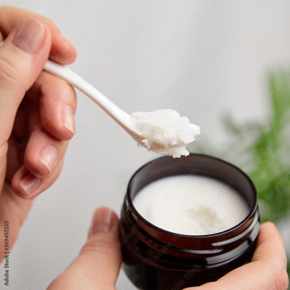 Female hand with pure shea butter in spoon. Anti-aging treatment. Skin and hair care product, natural cosmetics. Female hand with pure shea butter in spoon. Anti-aging treatment. Skin and hair care product, natural cosmetics.