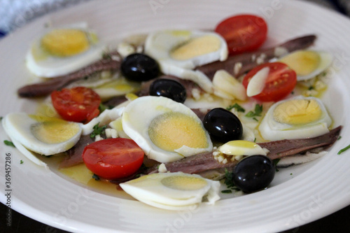 Anchovy salad with boiled egg, black olives and tomato