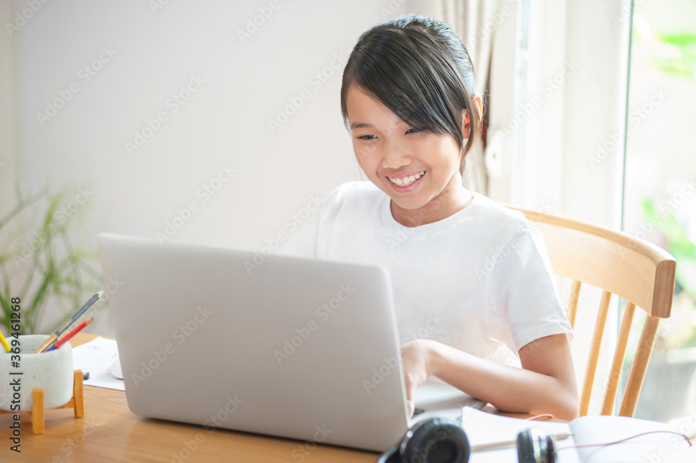 Smiling Little asian girl using laptop to learning online at home and typing on keyboard homeschool concept Smiling Little asian girl using laptop to learning online at home and typing on keyboard homeschool concept