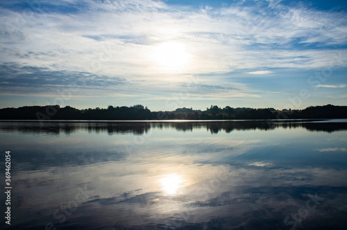 Contrasting clouds are reflected in the calm lake water.