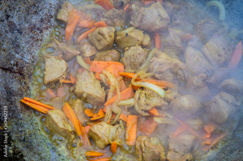 Cooking meat with vegetables, onions and carrots in a cauldron