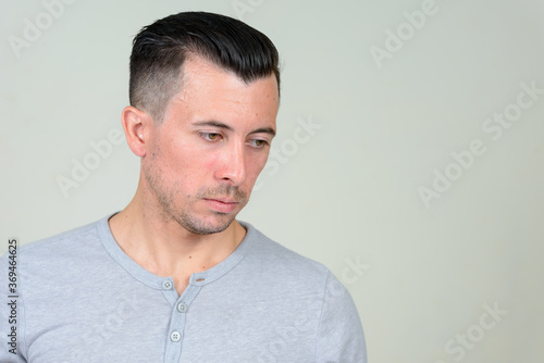 Portrait of young handsome man thinking and looking down