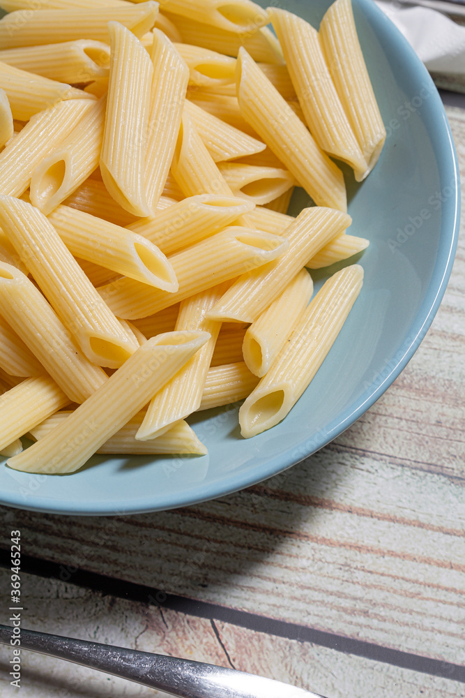 Penne pasta food served on a blue plate on a wooden table close up still Penne pasta food served on a blue plate on a wooden table close up still