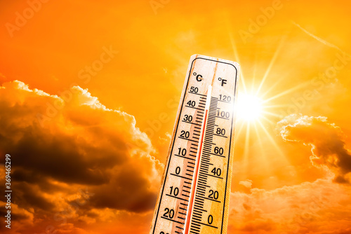 Fototapeta Hot summer or heat wave background, glowing sun on orange sky with thermometer