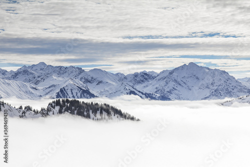Snow covered mountains with inversion valley fog and trees shrouded in mist. Scenic snowy winter landscape in Alps  Allgau  Kleinwalsertal  Bavaria  Germany.