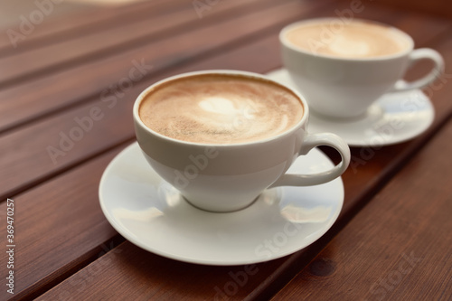 Two cups of cappuccino on the wooden background