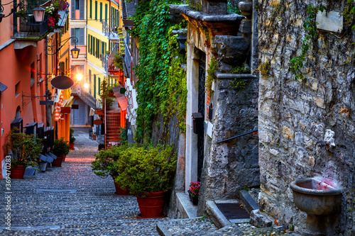 Bellagio, lake Como, Milan, Italy. Famous stone stairs street. Evening Nighttime with blue sky and lights of outdoor lanterns. Picturesque italian architecture of famous luxury Alpine health resort