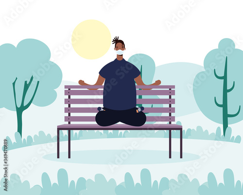 afro young man wearing medical mask practicing yoga in park chair