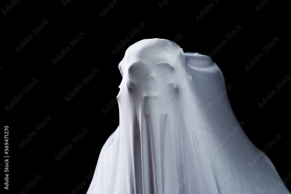 White ghost in white cloth on isolated black background. Face devil shouting covered curtain on blank. Halloween concept. White ghost in white cloth on isolated black background. Face devil shouting covered curtain on blank. Halloween concept.