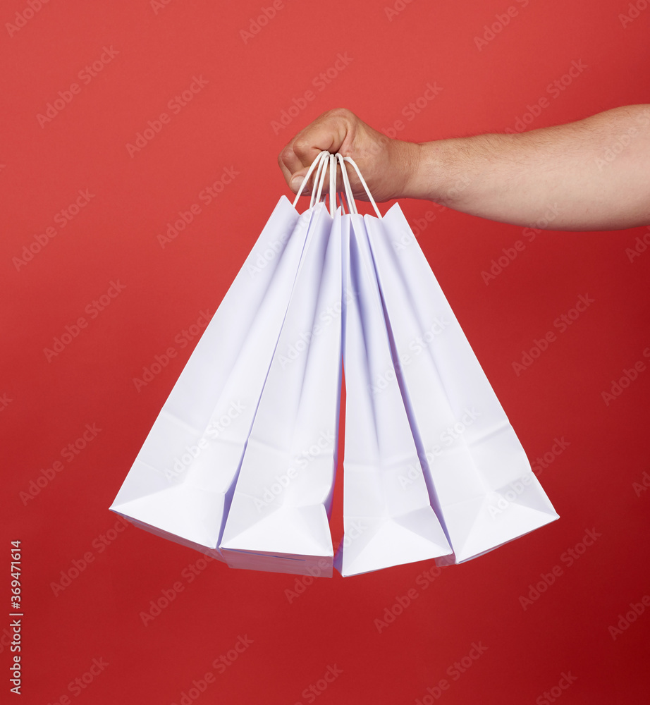 man in blue clothes holds a stack of white paper bags, red background man in blue clothes holds a stack of white paper bags, red background