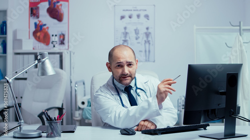 Young physician offering internet medical advice in modern private clinic hospital office. Doctor using internet technology to consult patients during covid-19 global pandemic. Telemedicine and