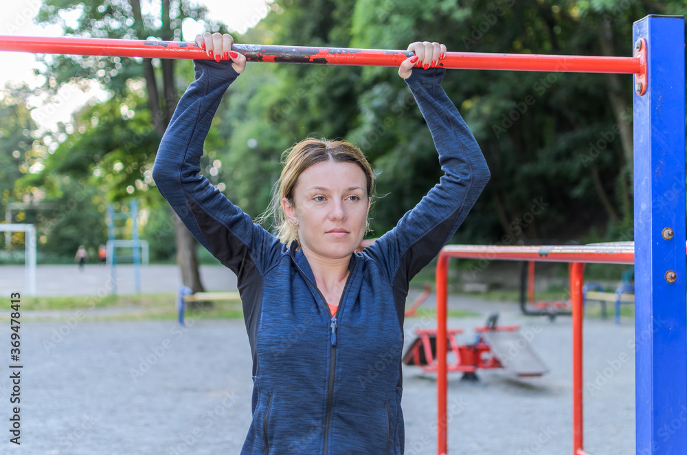 Fototapeta premium Young women doing sports on outdoor exercise machine in the stadium