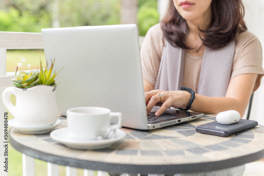 Businesswoman hands typing on a laptop at balcony with garden view. Businesswoman hands typing on a laptop at balcony with garden view.