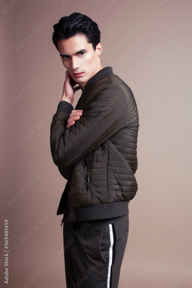 young pretty asian man posing in fashion style on light brown background, lifestyle people concept young pretty asian man posing in fashion style on light brown background, lifestyle people concept