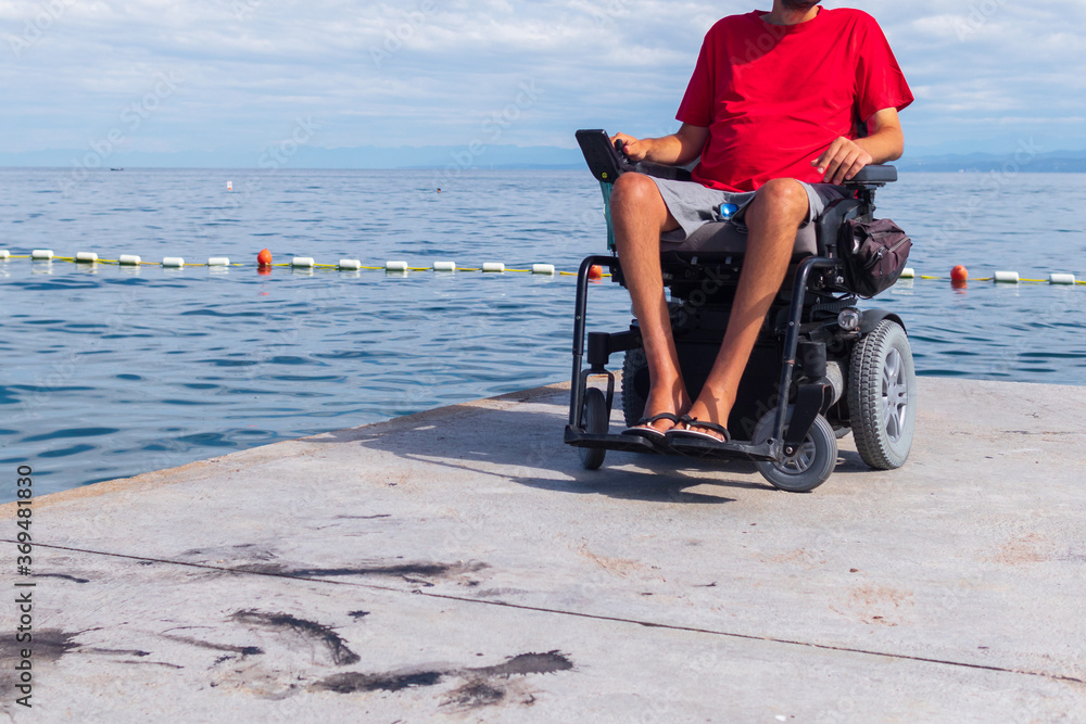 Man sitting in a wheelchair on the beach. Dangers of jumping into water