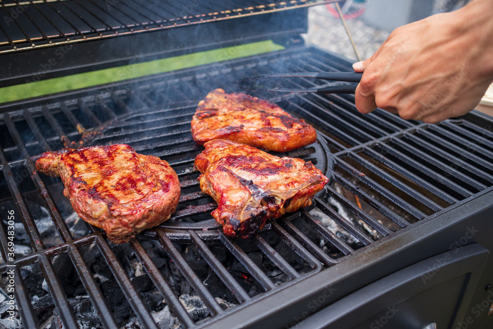 Home barbecue with charcoal in the backyard grilling steaks and other meats for carnivore diet.