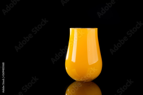 Glass of orange juice or hazy New England IPA on black background photo