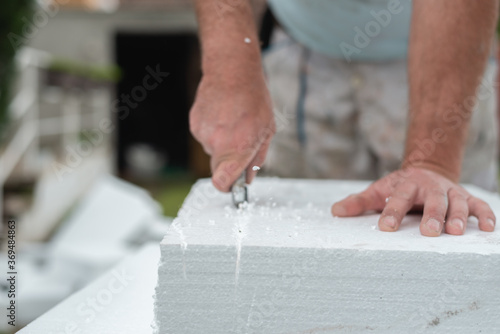 Close up of workers hand cutting styrofoam with precision knife