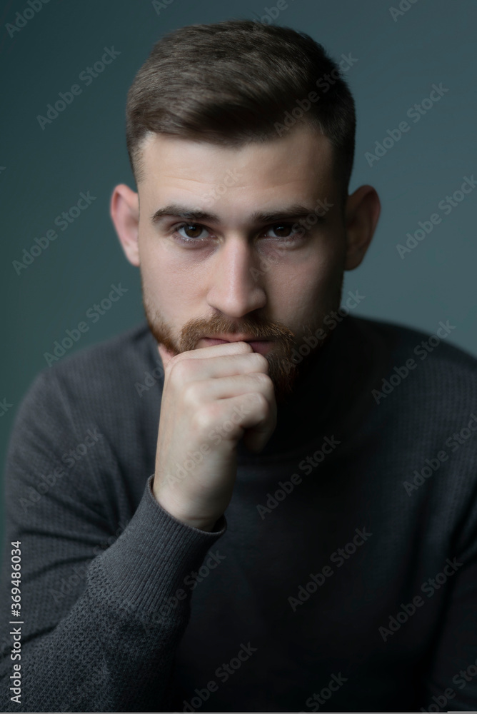 young bearded guy looks at the camera, on a gray background studio portrait. Psychological portrait. Handsome guy. Man of twenty five young bearded guy looks at the camera, on a gray background studio portrait. Psychological portrait. Handsome guy. Man of twenty five