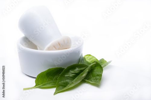 Mortar and Pestle with fresh Basil leaves isolated on a white background
