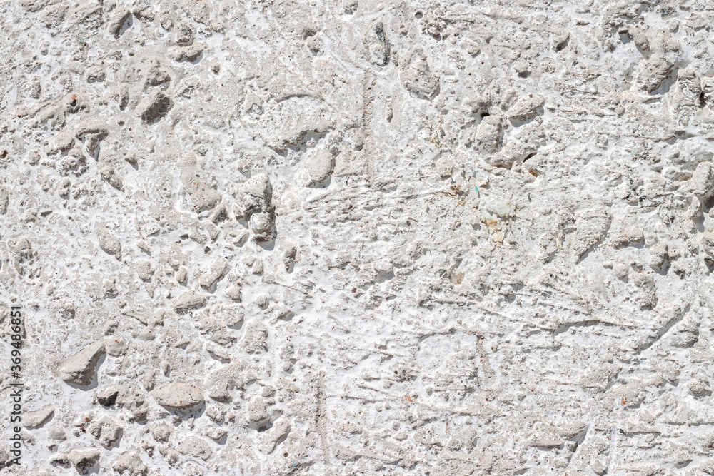 Concrete with rocks wall bumpy grey painted surface for cool urban grungy wallpaper or macro background Concrete with rocks wall bumpy grey painted surface for cool urban grungy wallpaper or macro background