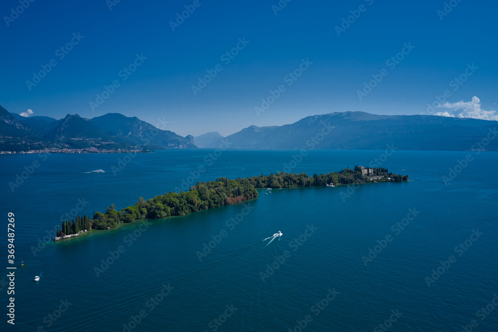 Is the biggest island on Lake Garda. Aerial view of the island Garda, Lake Garda, Italy. In the background Alps, blue sky.