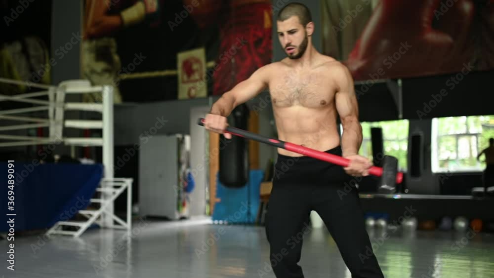 handsome bodybuilder with closed eyes is resting after doing sledgehammer exercises at the gym. full length side view handsome bodybuilder with closed eyes is resting after doing sledgehammer exercises at the gym. full length side view