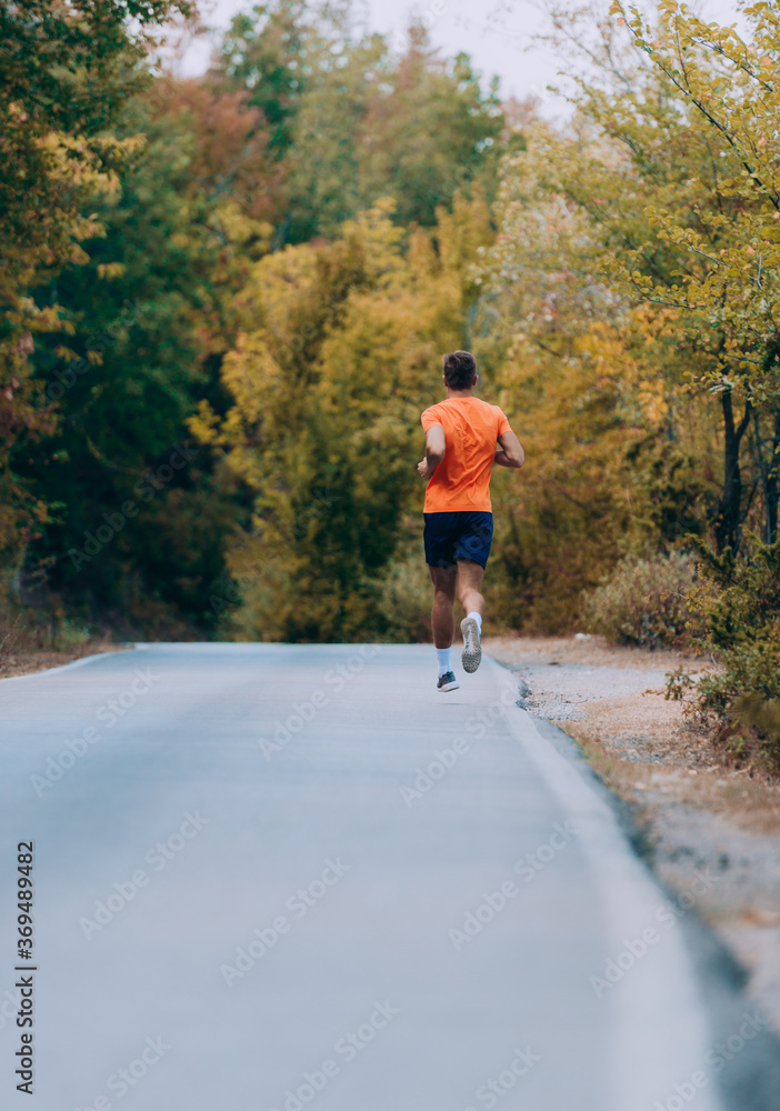 Fototapeta premium Fit handsome jogger working out for marathon outside in autumn