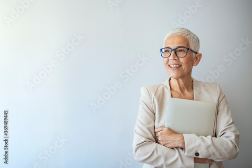 Foto Portrait of a beautiful elderly business woman, smiling, isolated on grey background
