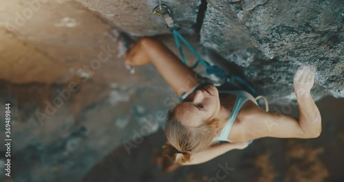 Incredible woman rock climbs mountain while friend belays her below, cinematic slow motion, fitness lifestyle photo