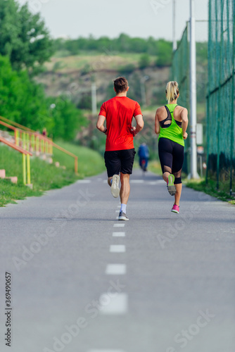 View from the back of a young sports couple running in the park
