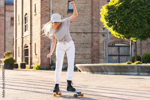 Stylish  girl trying to ride a longboard photo