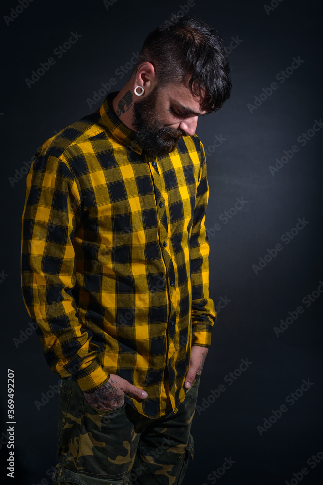 Profile portrait picture of a bearded man with tattoos on his face and neck in yellow black shirt Profile portrait picture of a bearded man with tattoos on his face and neck in yellow black shirt