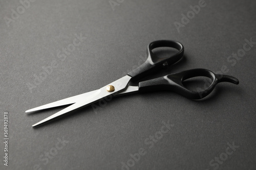 Black hairdresser scissors on black background, space for text