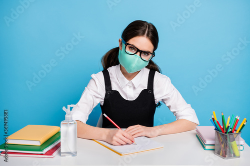 Portrait of her she nice attractive diligent girl in reusable safe mask sitting doing home work quarantine clean neat hands isolated on bright vivid shine vibrant blue color background