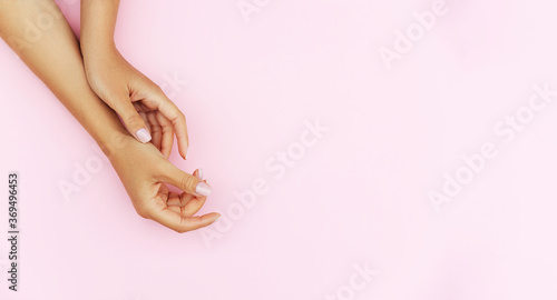 Tender hands with perfect blue and pink manicure on trendy pastel pink background. Place for text