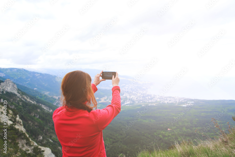 Closeup photo of cup with tea in traveler's hand over out of focus mountains view. A young tourist woman drinks a hot drink from a cup and enjoys the scenery in the mountains. Trekking concept.