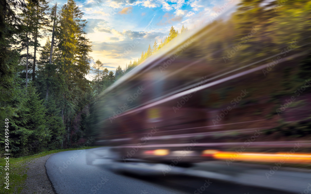 Blurred bus in motion is driving on mountain road in the autumn forest at sunset. Travel concept Blurred bus in motion is driving on mountain road in the autumn forest at sunset. Travel concept