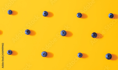 Seamless pattern with fresh sweet blueberry fruit on colorful yellow background. Dessert healthy food concept. Raw summer diet. Delicious nature vegetarian ingredient. Flat lay, minimal style