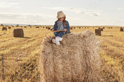 Reading girl sits over the haystack roll on field in countryside. High quality photo © Andy Shell