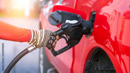 Close up worker hand holding nozzle for filling diesel fuel into red pick up car at refuel station