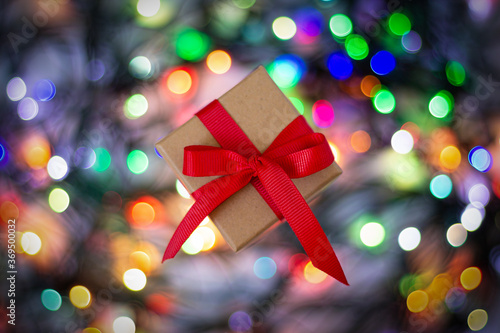 Gift box with red ribbon on colorful blurred bokeh lights background