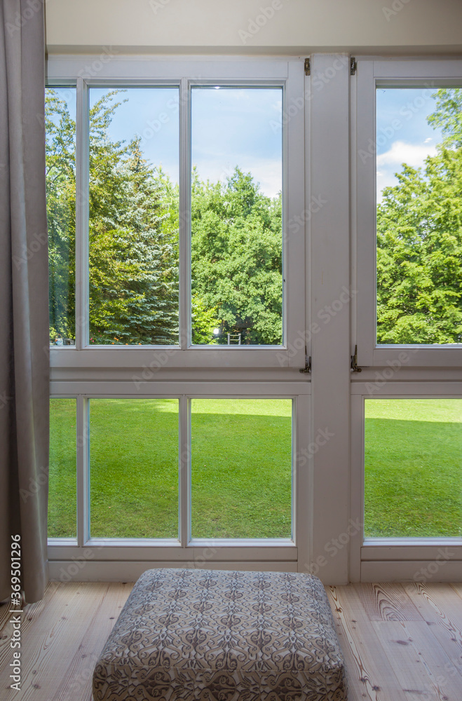 Fototapeta premium view of the window in the room on a green park on a sunny summer day