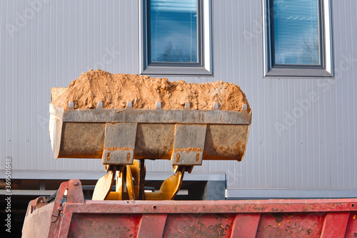Excavator loads dump truck soil on construction site. Backhoe dumping sand in tipper. Wheel loader loads sand into heavy mining dump truck. Digging and excavation operations
