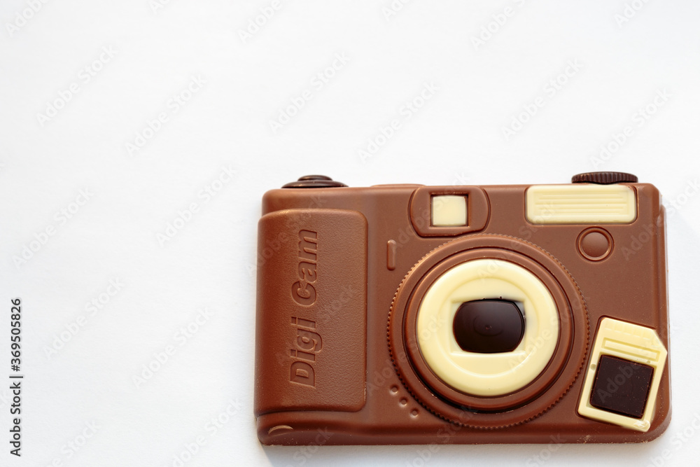 Horizontal view of a camera-shaped chocolate bar created from dark and white chocolate against white background. Gift idea for a photography enthusiast
