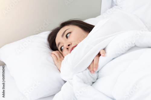 Young Woman Sleeping In Bed. Portrait Of Beautiful Female Resting On Comfortable Bed With Pillows in the morning. Happy woman sleeping on a pillow in bed and smiling. Pretty young girl on white bed.
