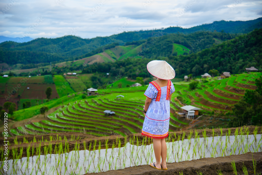 Young female traveler with hat enjoying beautiful view rice fields on terraced of Ban Pa Bong Piang in Chiangmai, Thailand