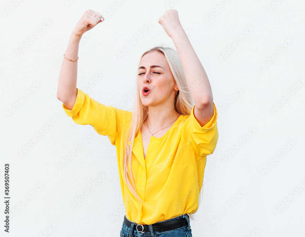 Portrait of raised fists up woman in casual wear isolated on white background with wide open mouth